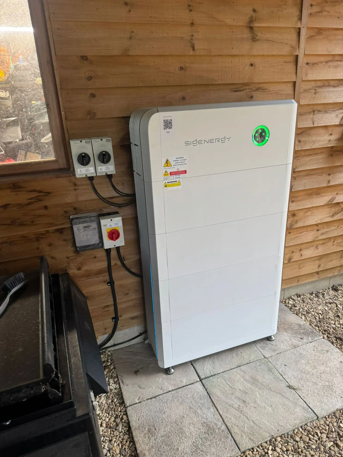 Sigenergy battery on outdoor wood-clad shed wall